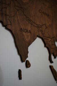Close-up of a wooden carved map showing countries in South Asia on a white wall.